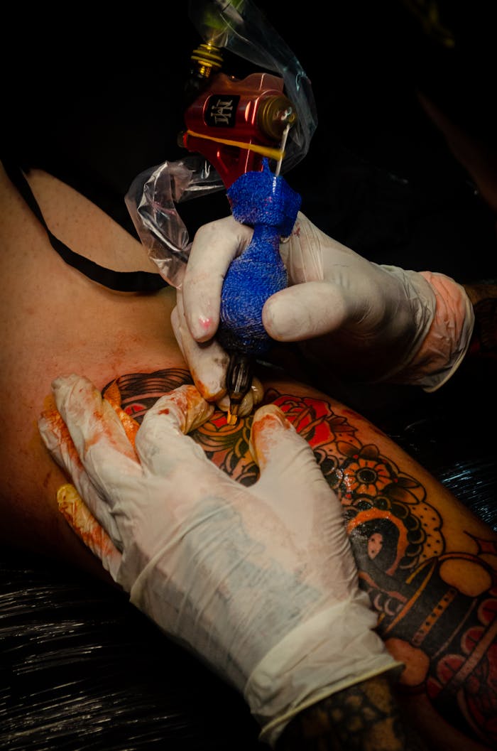 Tattoo artist working on a vibrant and colorful tattoo in a studio setting.