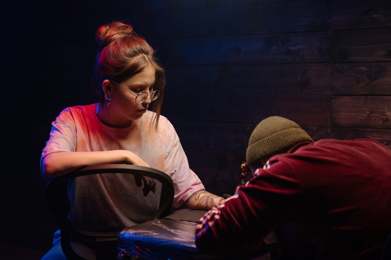 A focused tattoo artist creating detailed ink art on a client's arm in a stylish studio.